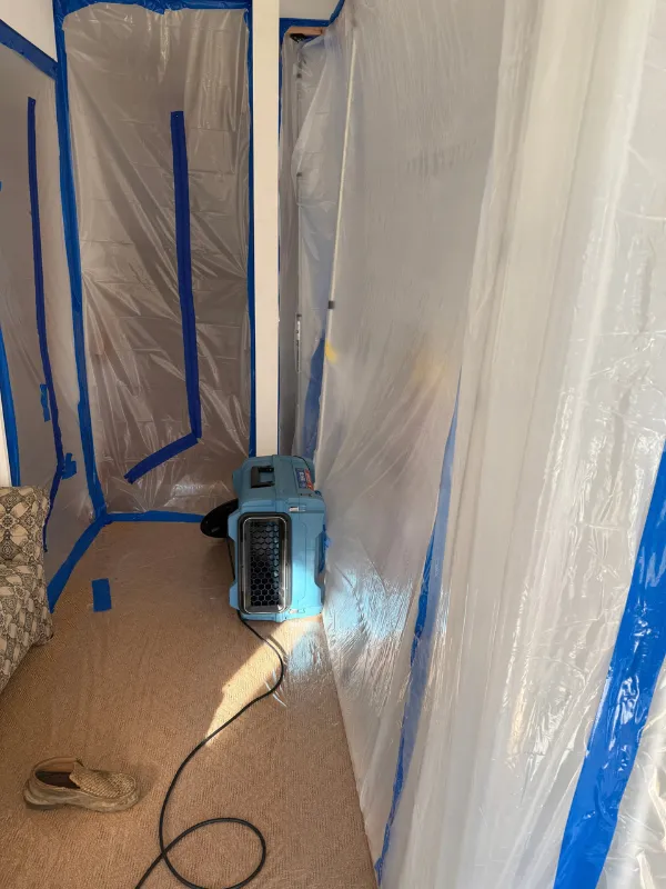 Air scrubber running inside a sealed containment area on a hardwood floor