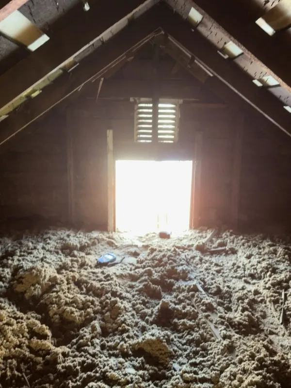 Blown-in attic insulation beside a gable vent