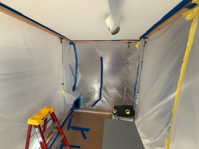 Containment sheeting and a ladder set up in a room being remediated