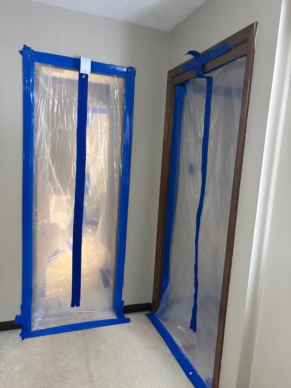 Plastic containment barrier taped across a doorway during mold remediation