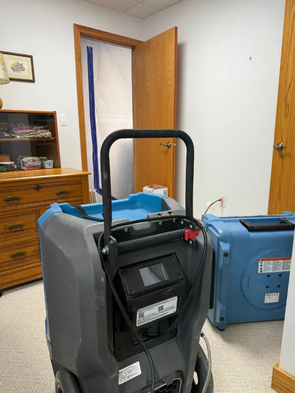 Dehumidifier and air mover drying a carpeted room after a water loss