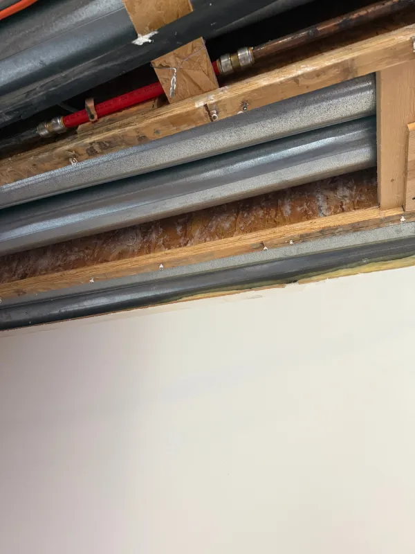 Insulated pipes running between floor joists in a crawl space