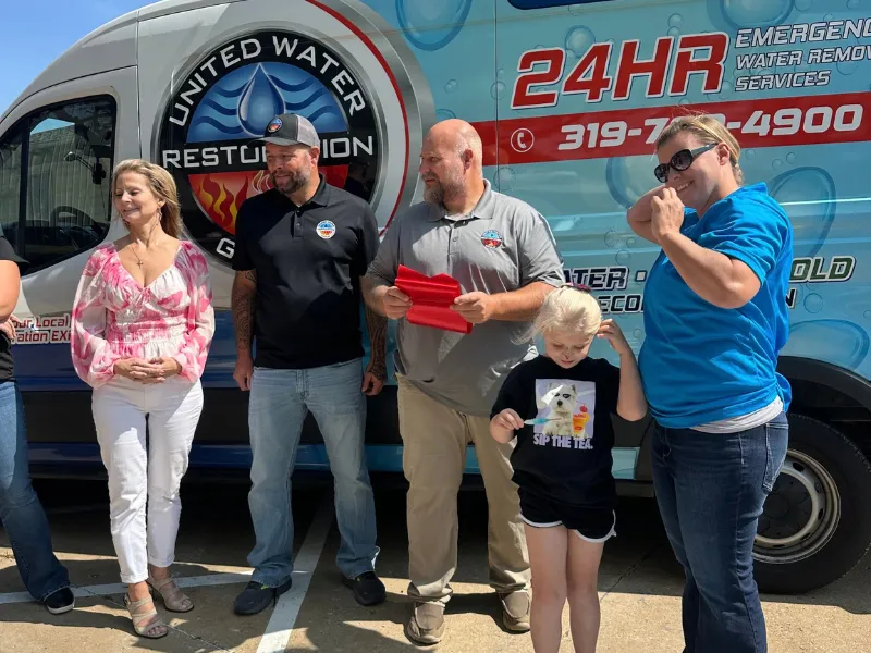 Ribbon-cutting celebration in front of a company van