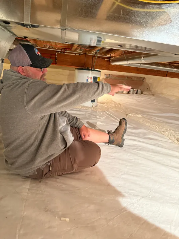 Technician working beneath floor joists in a crawl space