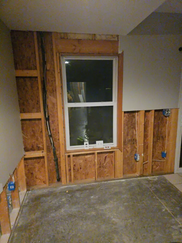 Wall framing exposed around a window after water-damaged drywall was removed
